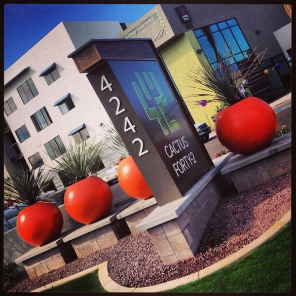 Bold orange-red sphere planters add drama at an apartment complex entrance