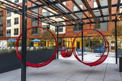 Red circular seating swings with rectangular planters in background
