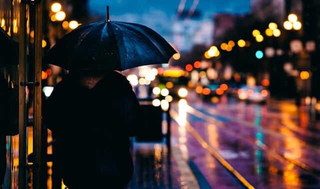 A person walking on a city street at night during the rain
